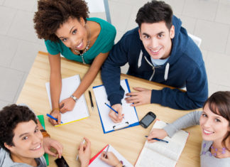 Group of young students studying together at library