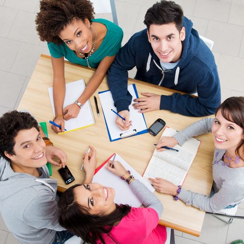 Group of young students studying together at library