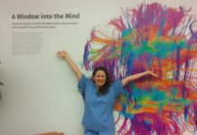 Susanna Zaraysky in scrubs in front of painting of the brain